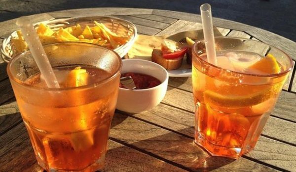 tavolino apparecchiato con due spritz e ciotole con salse e patatine